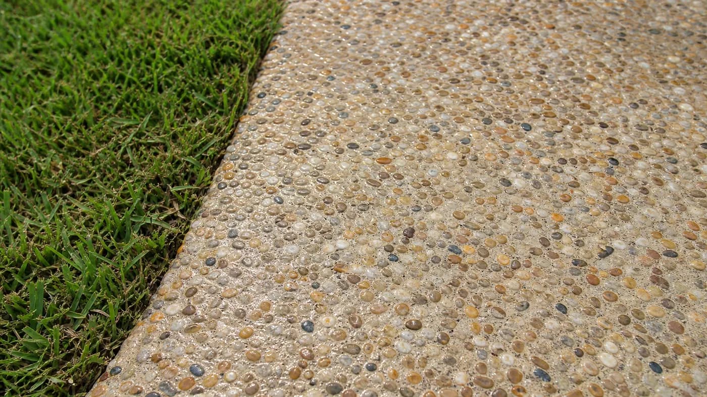 Exposed aggregate walkway with rounded tan and gray river pebbles, freshly sealed